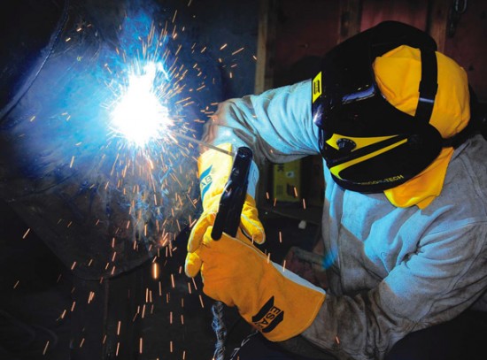 Imagem de um soldador trabalhando em projeto industrial com equipamentos de proteção